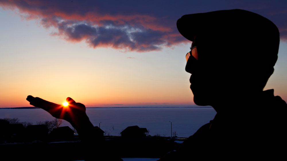 Man holding sun in silhouette at sunset. 