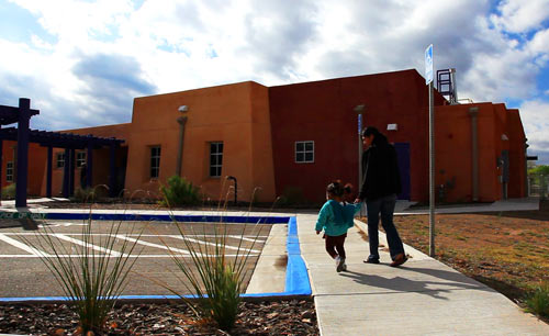 A student and her child walk into the campus learning center. 