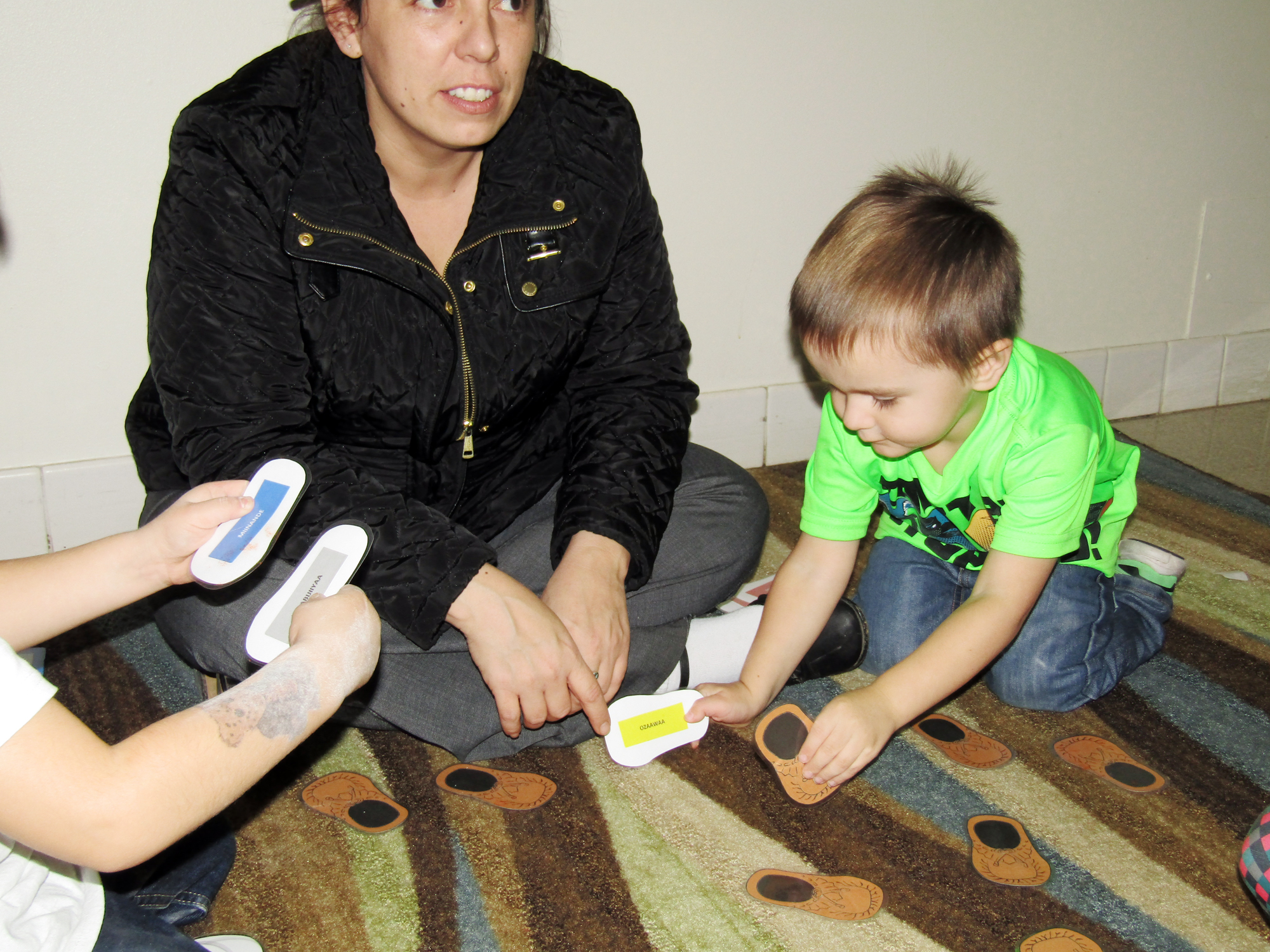 KBOCC cultural consultant engages children during a moccasin color matching game using Ojibwe words.