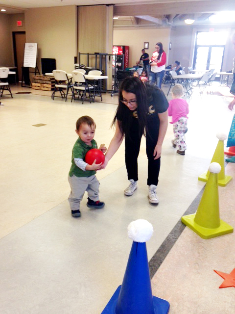 A toddler replaces the soft white ball on the yellow cone at the “Charging into a Healthy Future” at tribal college SKC event.