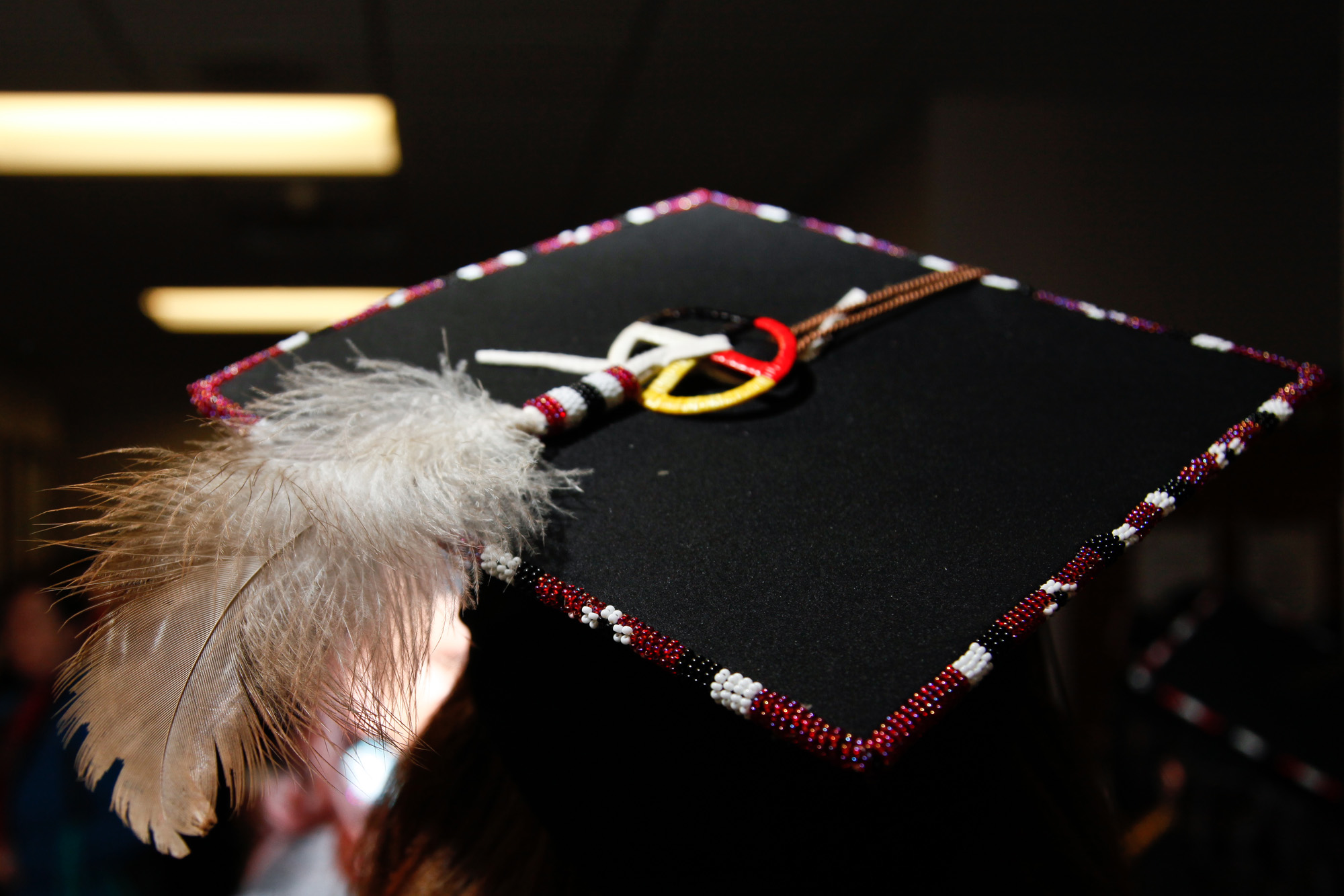A Native American student wears a mortarboard with an eagle feather and Native regalia at the United Tribes Technical College Spring Graduation.