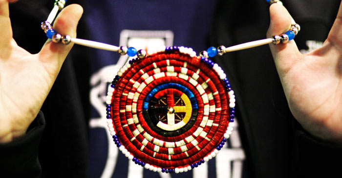 Dera adorns a hand-made quill medallion.
