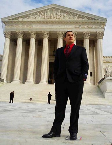 student standing outside the Supreme Court in a business suit
