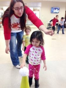 A toddler replaces the soft white ball on the yellow cone at the “Charging into a Healthy Future” at tribal college SKC event.