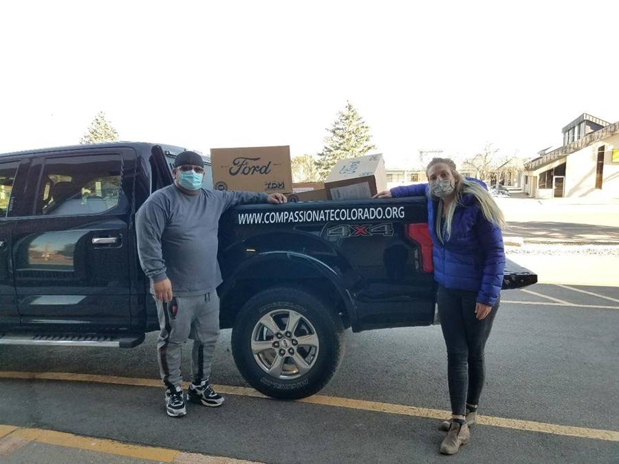 Justine Lenninger of the American Indian College Fund (right), helps load PPEs into a truck for Lucas Garcia, co-founder and Executive Director of Compassionate Colorado (left).