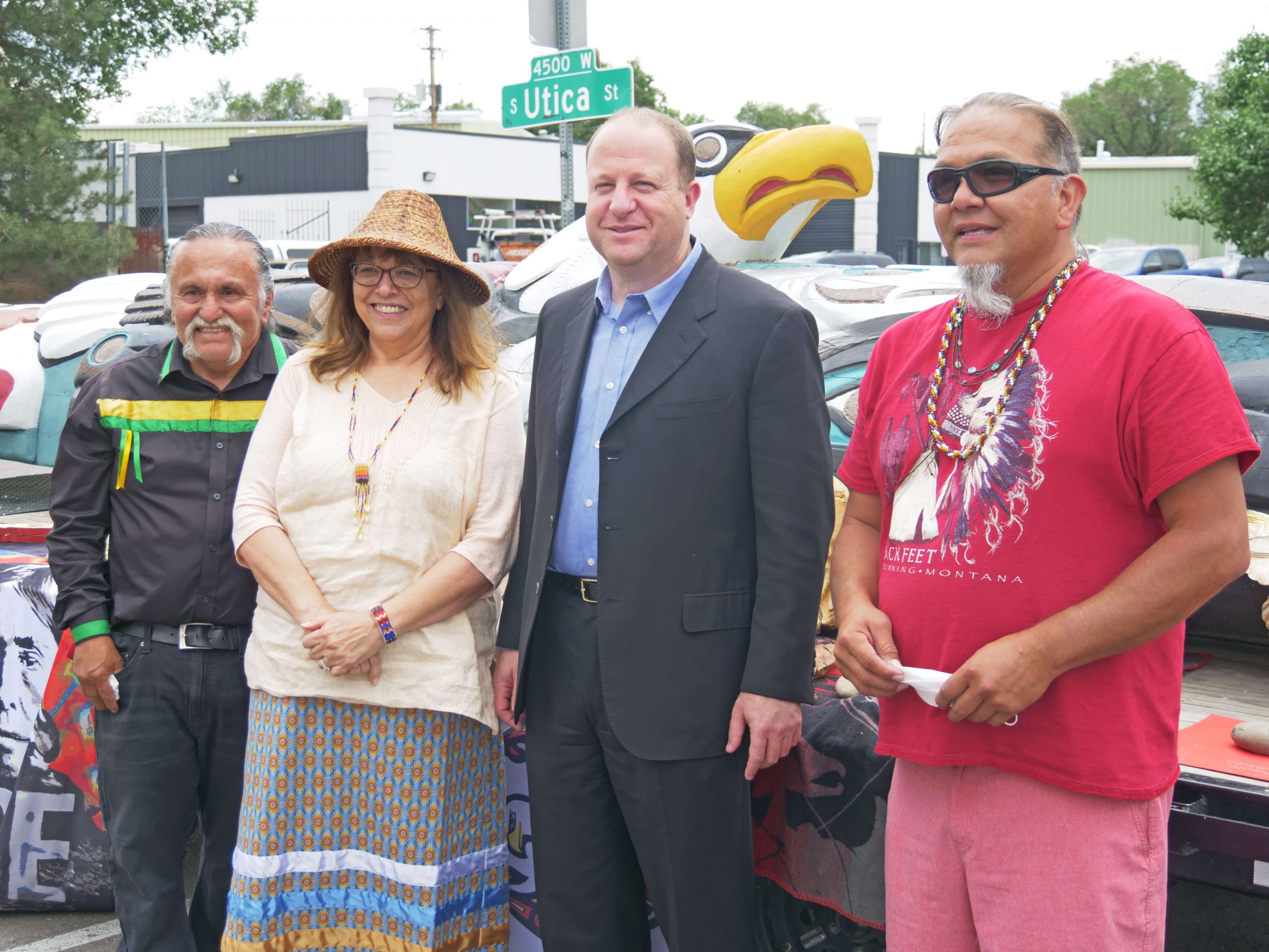 Cheryl Crazy Bull poses with Colorado Governor Polis (center) and Lummi artists with their totem pole.