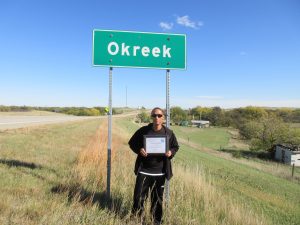 Stallan stands with his GED diploma near his home in Okreek, South Dakota.