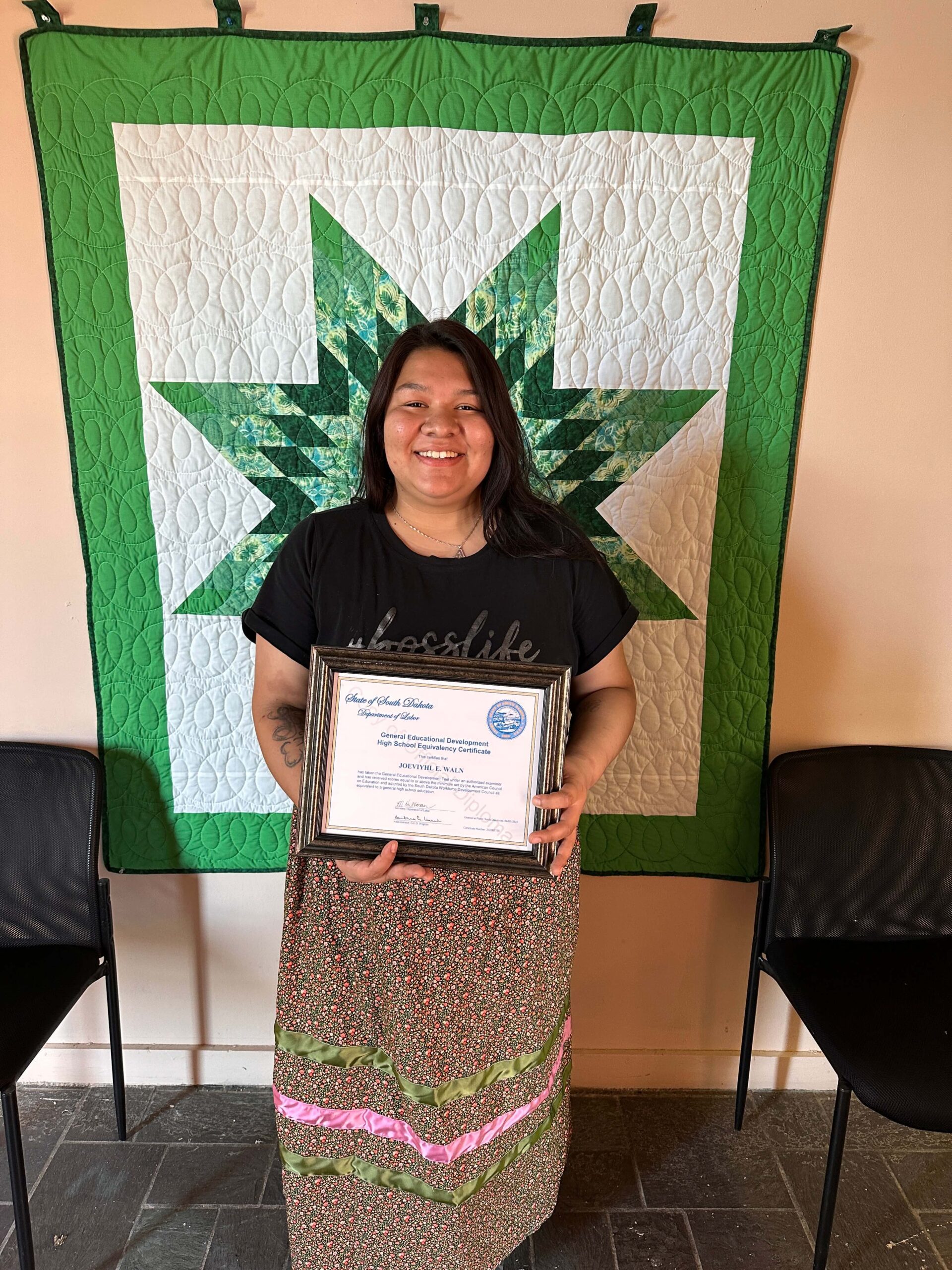 Jo Waln wearing her ribbon skirt while receiving her GED diploma at the Adult Basic Education office.