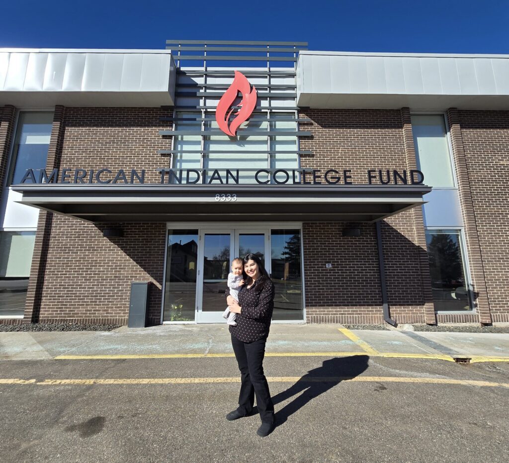 Heather Burshia and her baby standing at the front of the American Indian College Fund building for the 2023-2024 Indigenous Visionaries: Women’s Leadership Program convening in Denver, Colo.